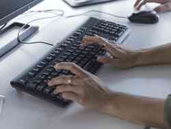 Zwei Hände tippen auf einer Computer-Tastatur
